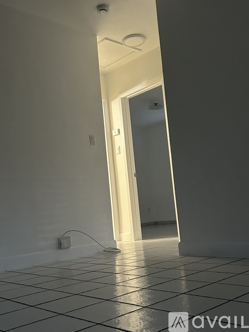 A hallway with a door at the end and a tiled floor.