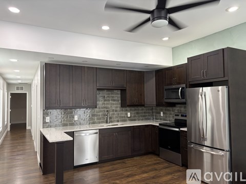 A modern kitchen with dark wood cabinets and stainless steel appliances.