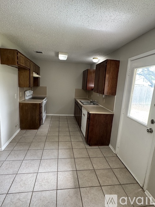 A kitchen with white walls and brown cabinets.