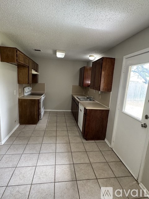 A kitchen with white walls and brown cabinets.
