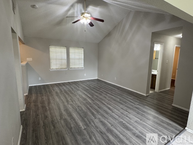 A spacious room with a ceiling fan and wood flooring.