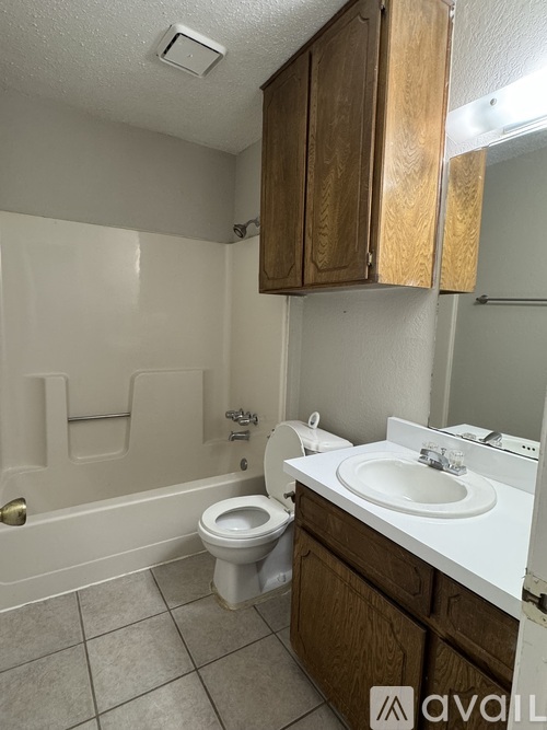A bathroom with a toilet, sink, and wooden cabinets.