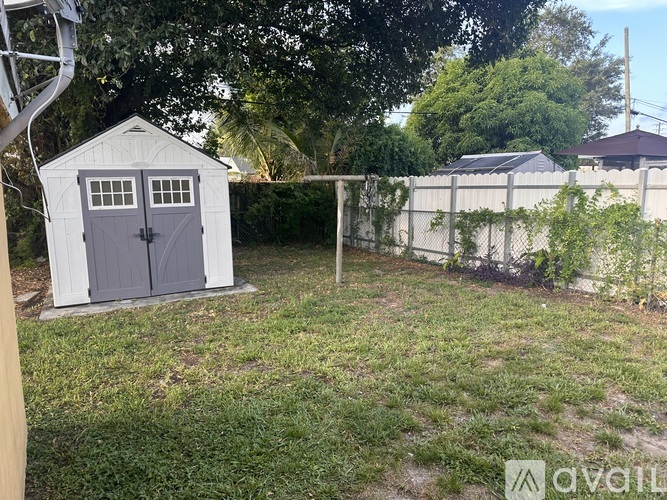 A shed with a grey door is in a yard.