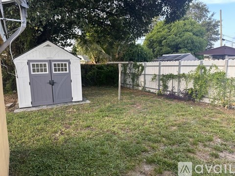 A shed with a grey door is in a yard.