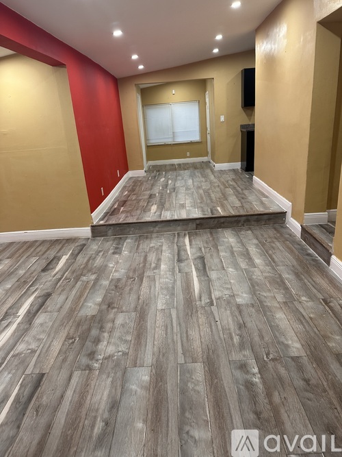 A room with wooden flooring and a red wall.