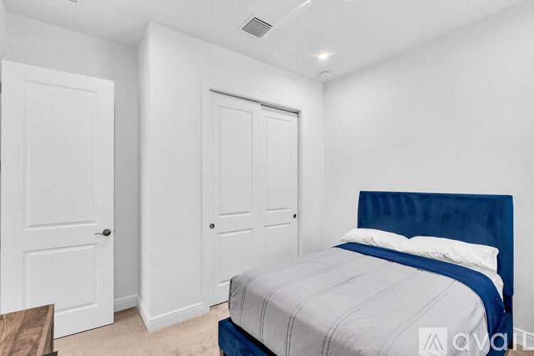 A bedroom with a bed, two doors, and a nightstand.