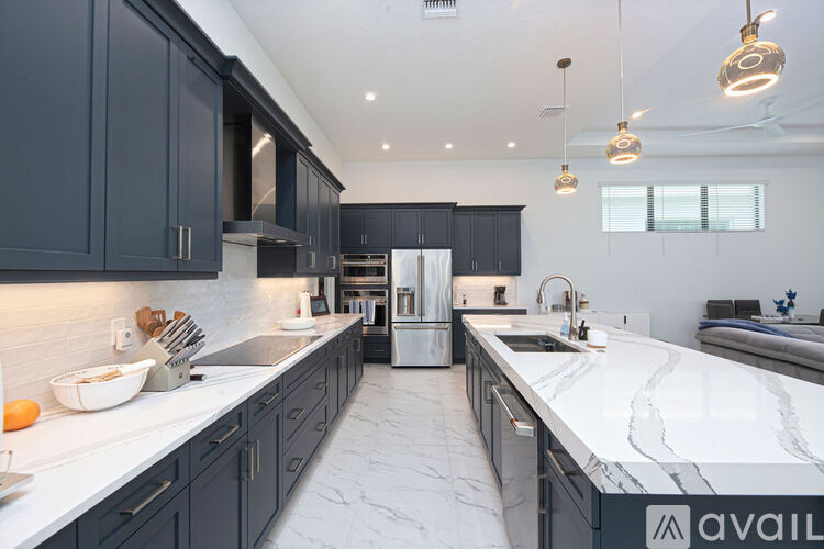 A modern kitchen with dark cabinets and marble countertops.