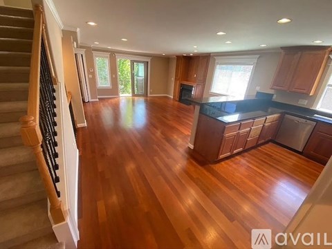A spacious kitchen with wooden floors and a staircase on the left side.
