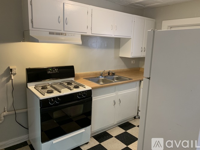 A black and white checkered floor in a kitchen with a stove, sink, and cabinets.