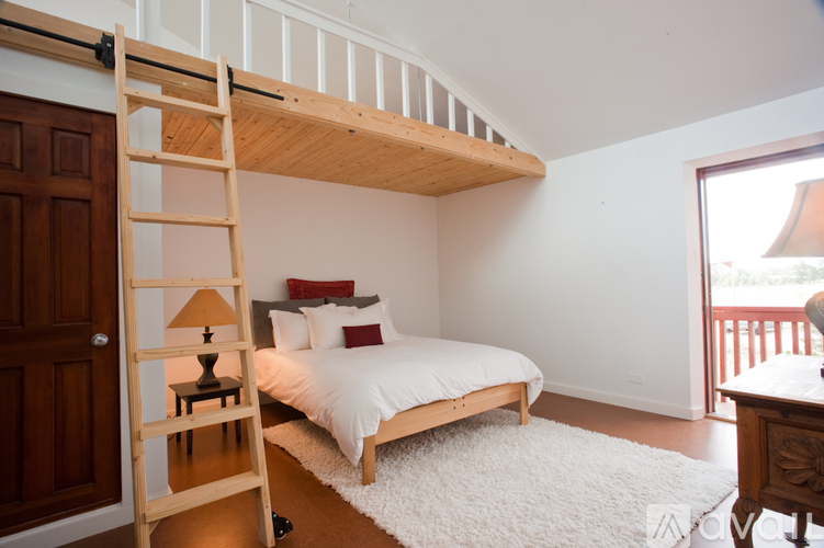 A bedroom with a white bed and a wooden ladder.