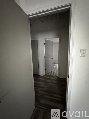 A hallway with a door on the right and a light switch on the wall.