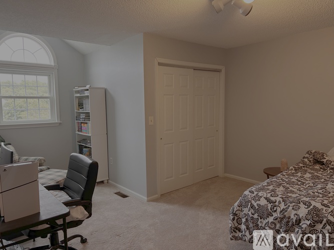 A bedroom with a bed, chair, and window.