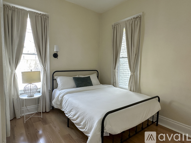 A bedroom with a large bed and a window with curtains.
