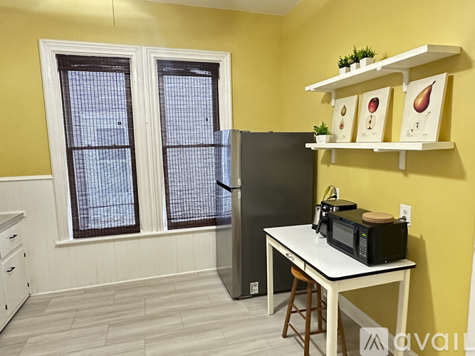 A kitchen with a refrigerator, microwave, and a table with a plant on it.