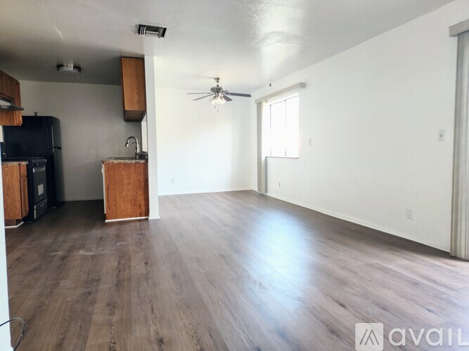 A spacious room with wooden flooring and a ceiling fan.