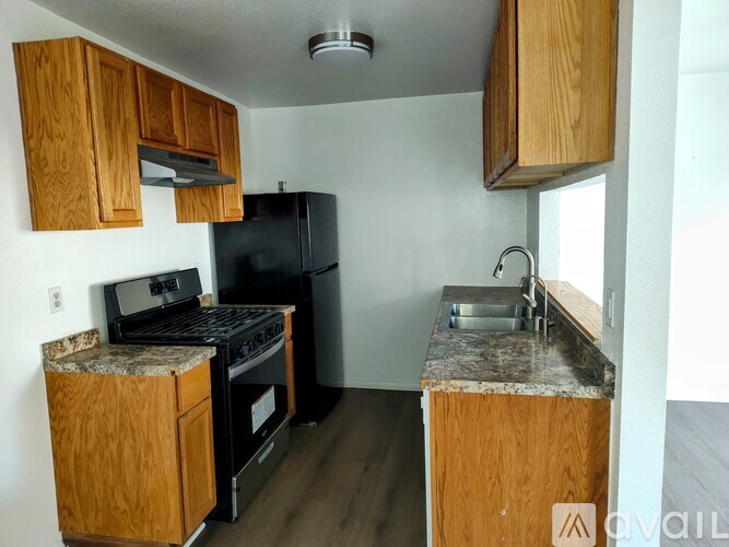 A kitchen with wooden cabinets and a black fridge.