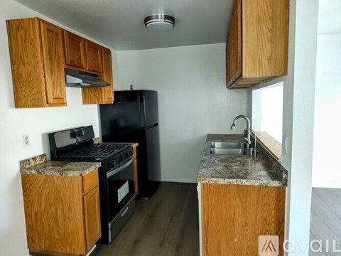 A kitchen with wooden cabinets and a black fridge.