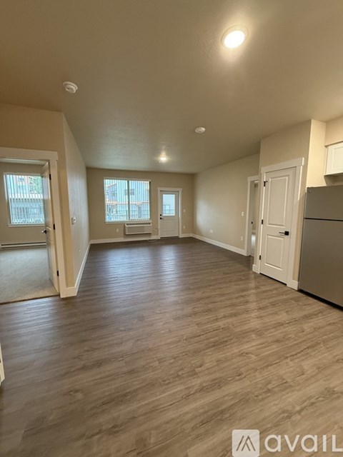 A spacious room with wooden flooring and white walls.