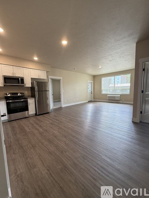 A spacious kitchen with stainless steel appliances and wooden flooring.