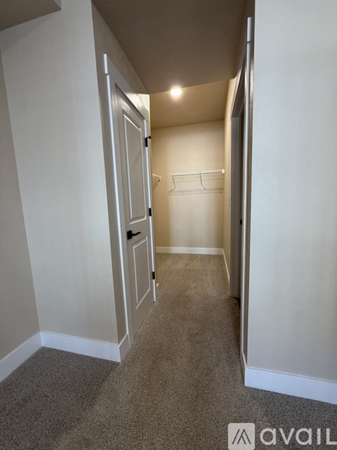 A hallway with a door on the left and a coat rack on the right.