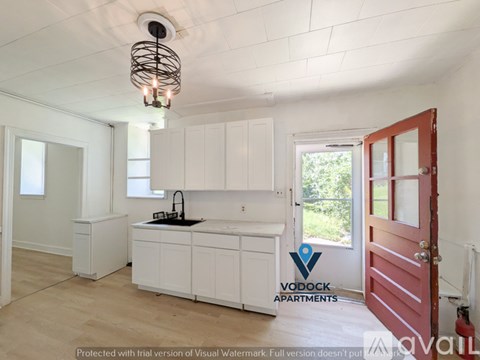 A kitchen with white cabinets and a red door.