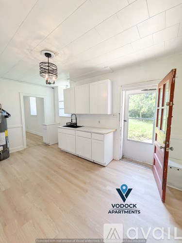 A kitchen with white cabinets and a wooden floor.