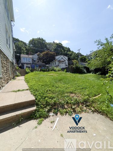 A grassy area with a sign for Vodock Apartments and Avail.