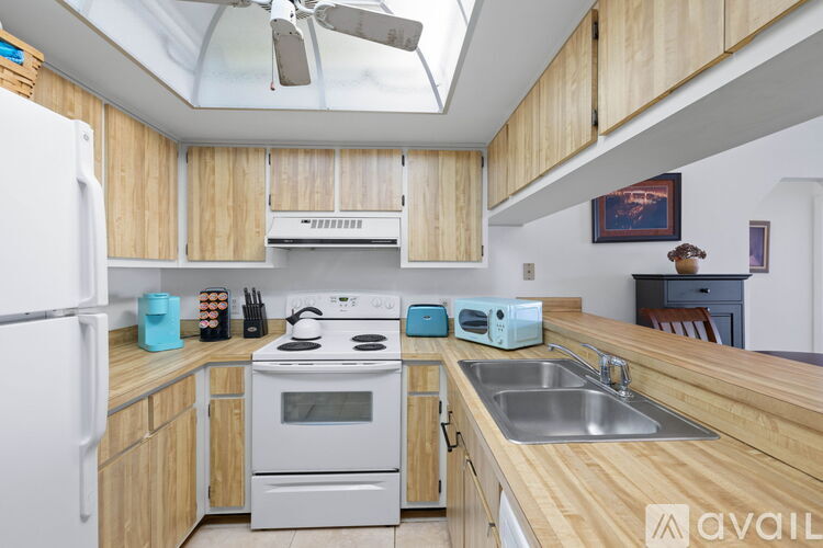 A kitchen with wooden cabinets and a white stove top oven.