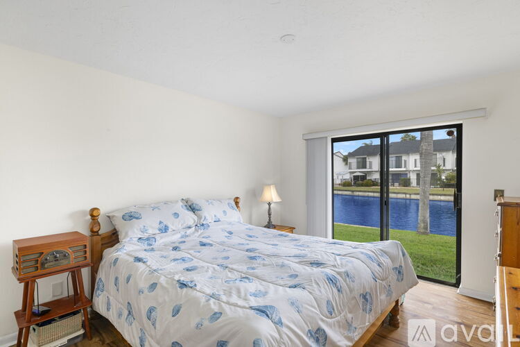 A bedroom with a bed, nightstand, and a window overlooking a body of water.