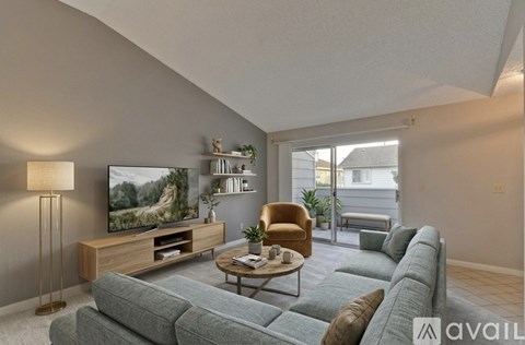 A living room with a grey couch, a wooden entertainment center, and a lamp.