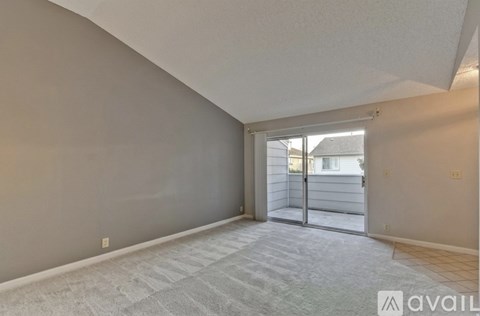 A room with a carpeted floor and a sliding glass door leading to a balcony.