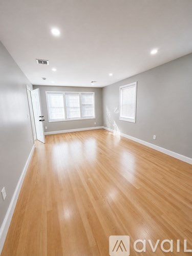 A room with wooden flooring and a door leading to another room.