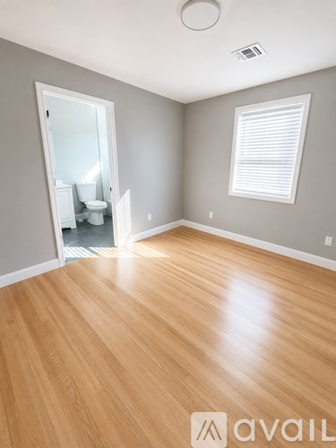 A room with wooden flooring and a window with blinds.
