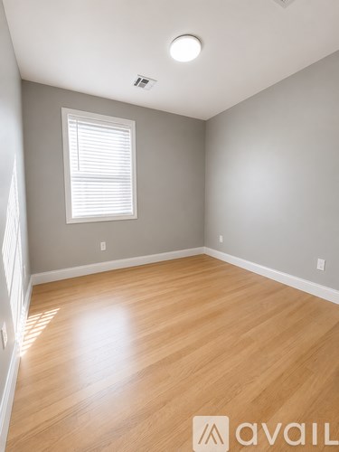 A room with wooden flooring and a window with blinds.