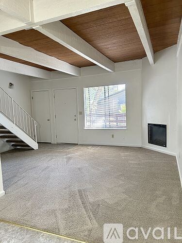 A spacious living room with a staircase and a flat-screen TV.
