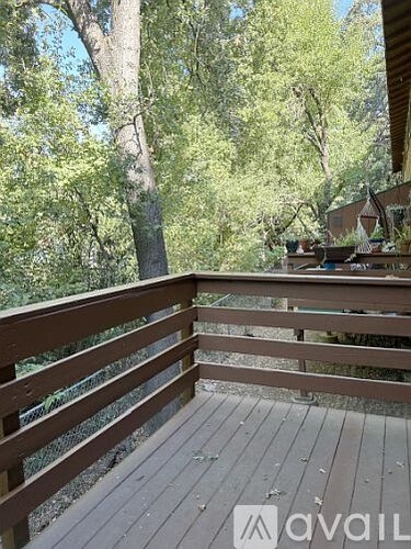 A wooden deck with a railing and trees in the background.