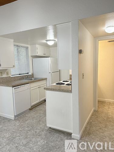A kitchen with white cabinets and a granite countertop.