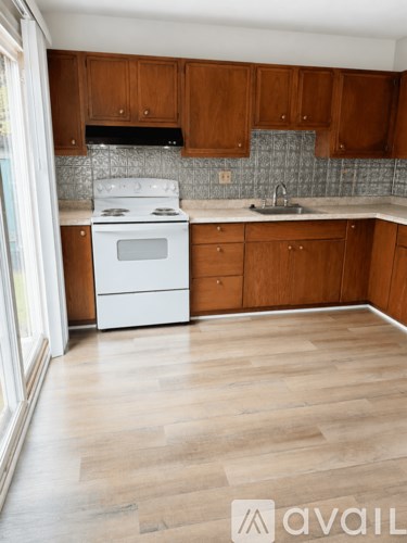 A kitchen with wooden cabinets and a white stove top oven.