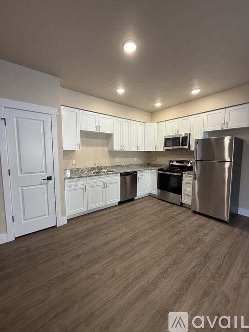 A kitchen with white cabinets and a wooden floor.