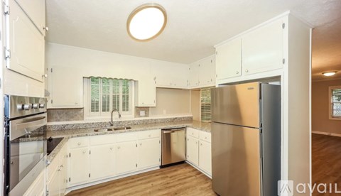 A kitchen with white cabinets and a stainless steel refrigerator.