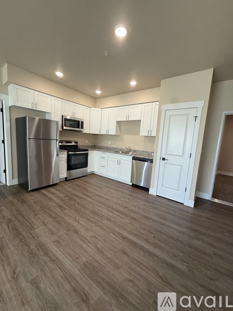 A kitchen with white cabinets and a wooden floor.