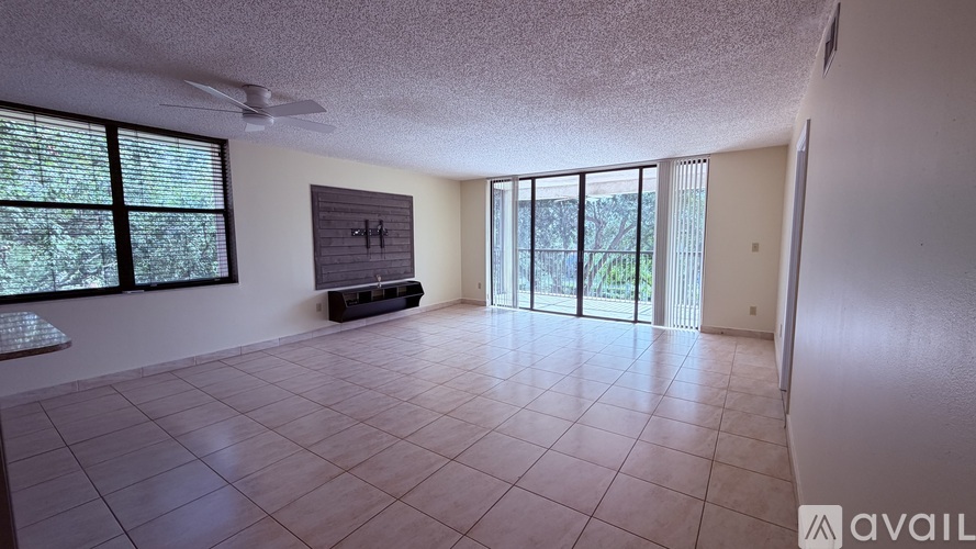 A spacious room with tiled flooring and sliding glass doors leading to a balcony.
