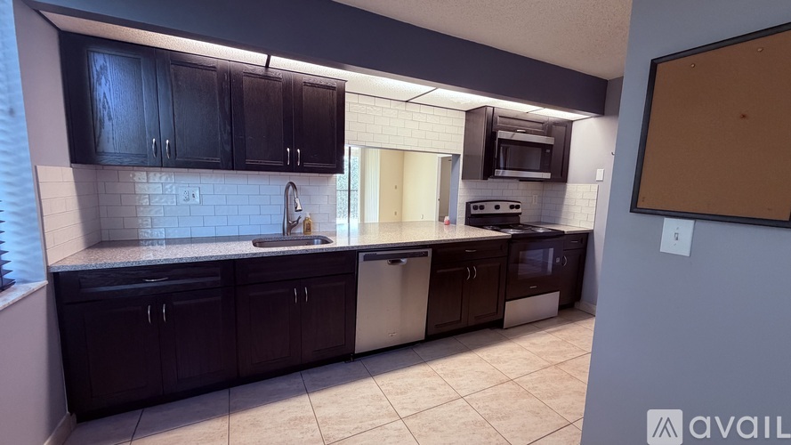 A kitchen with dark brown cabinets and a white backsplash.