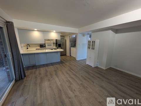 A spacious room with wooden flooring and a kitchen area with a sink and stove.