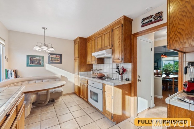 A fully furnished kitchen with wooden cabinets and a white countertop.
