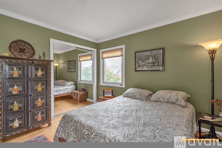 A bedroom with a large bed and a wooden cabinet with drawers.