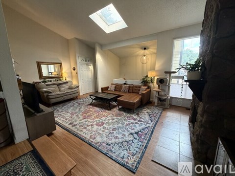 A living room with a skylight and a rug on the floor.