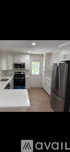 A kitchen with white cabinets and a stainless steel refrigerator.