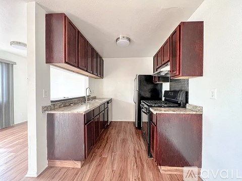 A kitchen with dark wood cabinets and a black refrigerator.