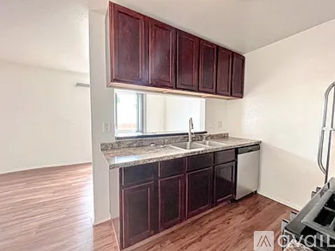 A kitchen with dark wood cabinets and a granite countertop.